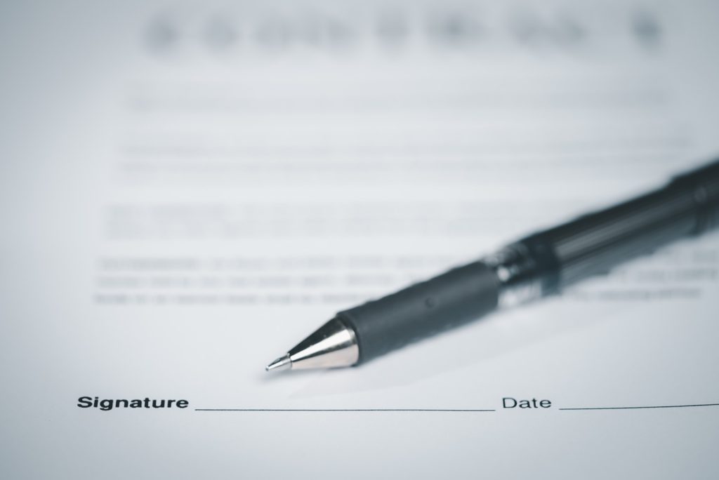 A close-up of a pen resting on a signed employment agreement, representing at-will employment under California Labor Code section 2922.