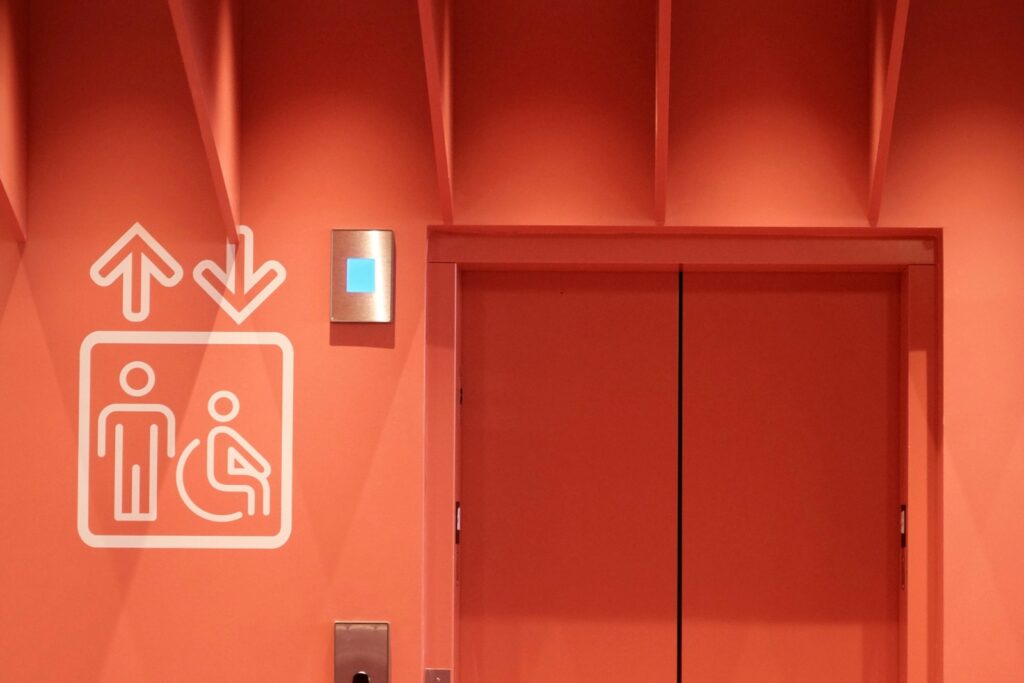 Elevator doors marked with an accessibility symbol, representing a landlord’s duty under California’s FEHA to keep elevators and other accessibility features working for disabled tenants.
