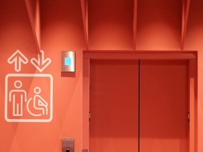 Elevator doors marked with an accessibility symbol, representing a landlord’s duty under California’s FEHA to keep elevators and other accessibility features working for disabled tenants.