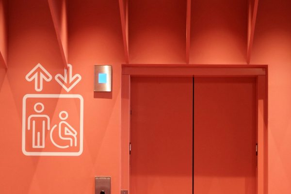 Elevator doors marked with an accessibility symbol, representing a landlord’s duty under California’s FEHA to keep elevators and other accessibility features working for disabled tenants.