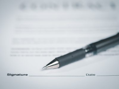 A close-up of a pen resting on a signed employment agreement, representing at-will employment under California Labor Code section 2922.