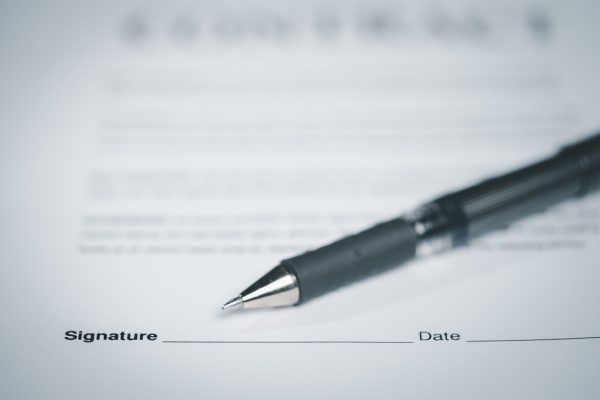 A close-up of a pen resting on a signed employment agreement, representing at-will employment under California Labor Code section 2922.