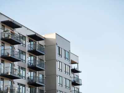 A modern multi-unit apartment building with balconies against a clear sky, representing California tenant rights and rent-stabilized rental housing.