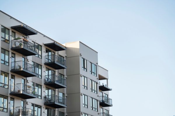 A modern multi-unit apartment building with balconies against a clear sky, representing California tenant rights and rent-stabilized rental housing.