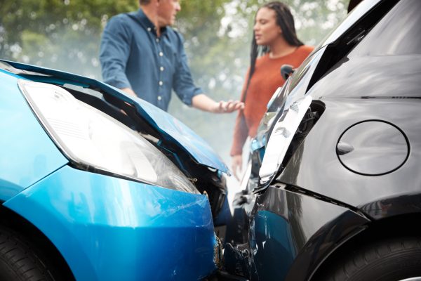 Two cars, one blue and one black, are shown after a head-on car accident. In the background, a man and woman discuss What to Do After a Car Accident. Both vehicles have significant front-end damage, highlighting the importance of protecting your rights after a crash.